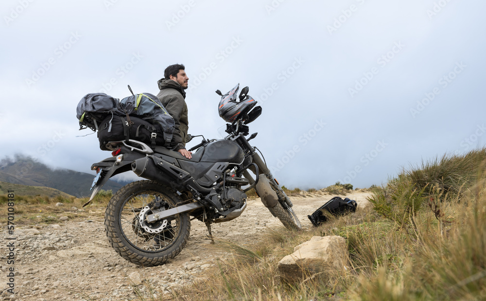 Motorcyclist man stands with the adventure motorcycle.Motorbike on the top of the mountain. Motorcycle trip. off road.