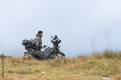 Motorcyclist man stands with the adventure motorcycle.Motorbike on the top of the mountain. Motorcycle trip. off road.