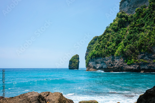 Tropical cove Tembeling Beach and Forest on Nusa Penida. Sunny day with clear sea, green cliffs and blue sky as copy space.
