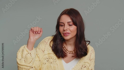 Knock-knock who is there, anybody home. Confused pretty woman knocking door gesture asking who is at home, feeling embarrassed, no idea, being clueless and uncertain. Young girl on gray background