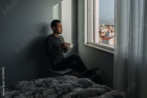 Asian man is having breakfast by the windows in the apartment.