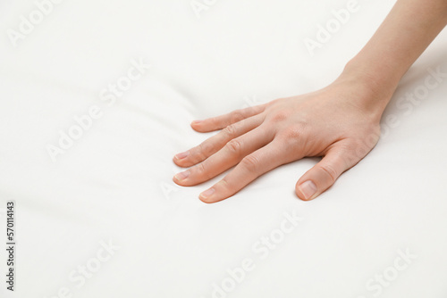 Woman touching orthopedic mattress, closeup. Space for text