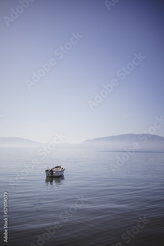 Small boat floating on the empty quiet sea. Concept of calm and serenity.