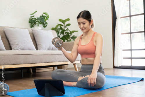 Young woman exercising at tablet having online training at home