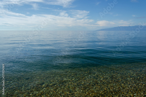 Lake Baikal on a sunny summer day. The smooth surface of the lake merges with the horizon.