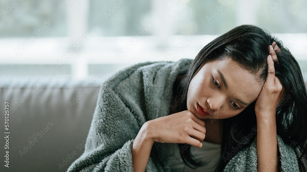 Unhappy sad Asian woman in a cloak suffering from fever and flu with headache Unhappy sad Asian woman in a cloak suffering from fever and flu with headache