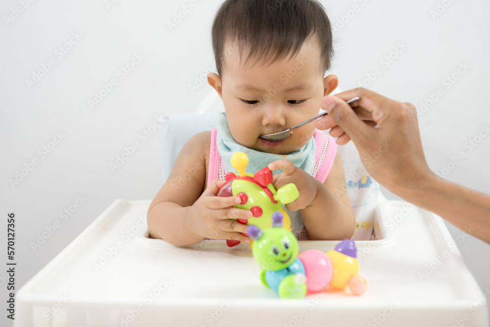 father feeding her baby boy with a spoon father feeding her baby boy with a spoon