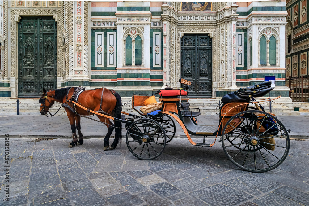 Horse drawn carriage by the colored marble facade of Duomo Cathedral or Cattedrale di Santa Maria del Fiore in Florence, Italy waiting for tourists