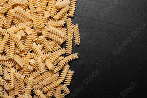  raw shaped pasta with space for text on black table in white light