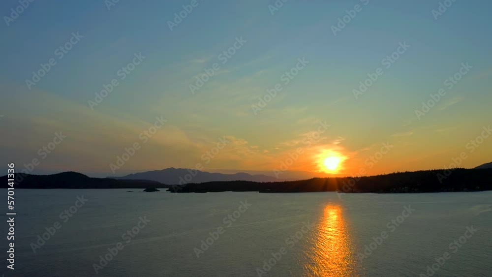Establishing aerial shot of ocean sunset over mountains in slow motion at summer day in Vancouver, Canada, North America. Evening time on September 2022. Drone flying. ProRes 422 HQ. Establishing aerial shot of ocean sunset over mountains in slow motion at summer day in Vancouver, Canada, North America. Evening time on September 2022. Drone flying. ProRes 422 HQ.