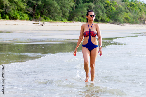 Woman with swimsuit walking in morning at beach