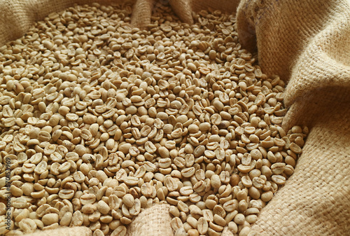 Heap of unroasted coffee beans in a burlap bag