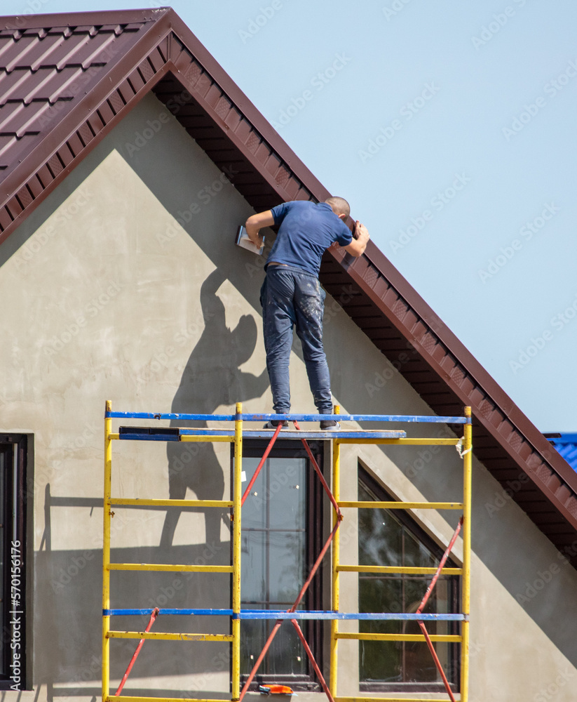 Workers are plastering the walls of the house outside. Cottage