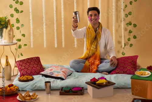 A young man is drinking a glass of bhang on holi festival photo