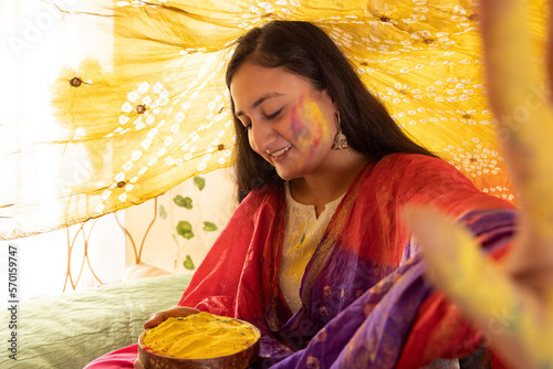 happy young woman holding a bowl of gulal on the occasion of holi