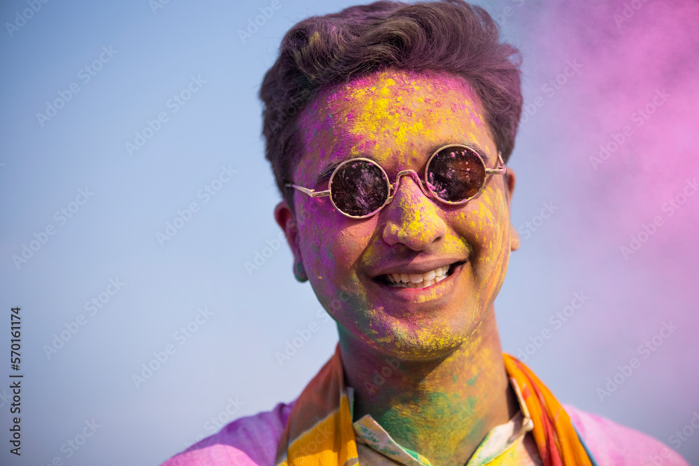 a young man with colour on his face is happily posing in front of camera a young man with colour on his face is happily posing in front of camera