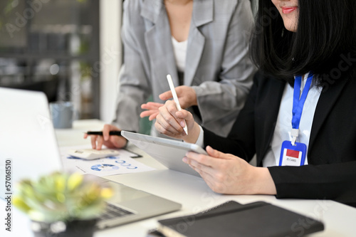 Confident Asian businesswoman using tablet and discussing work with her assistant. cropped