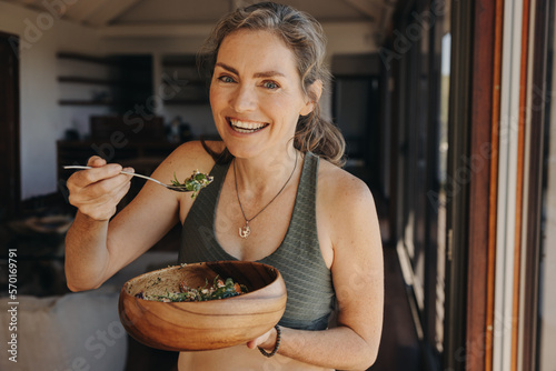 Happy vegan woman eating a vegetable salad from a bowl