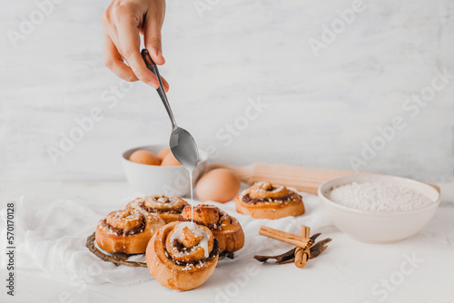 hands of woman making cinnamon rolls at table, recipe ingredients  photo