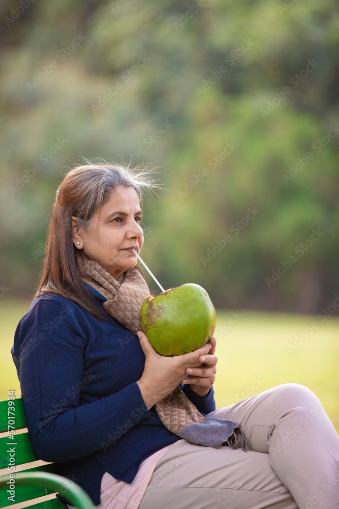 Indian senior woman drinking coconut water at park Indian senior woman drinking coconut water at park