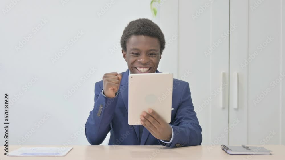 Young African Businessman Cheering Win on Digital Tablet Young African Businessman Cheering Win on Digital Tablet