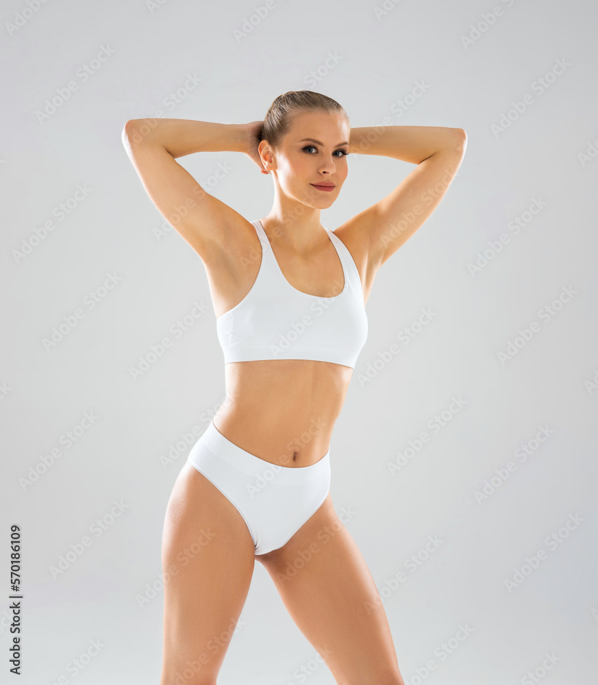 Young, fit and beautiful blond woman in white swimsuit isolated on grey background. Healthcare, diet, sport and fitness concept. Young, fit and beautiful blond woman in white swimsuit isolated on grey background. Healthcare, diet, sport and fitness concept.