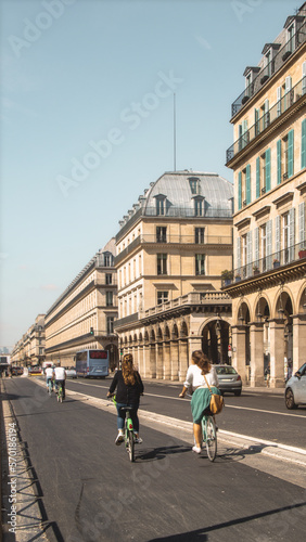 Photography vertical view of Paris street avenue on a sunny day with two girls going on a bi