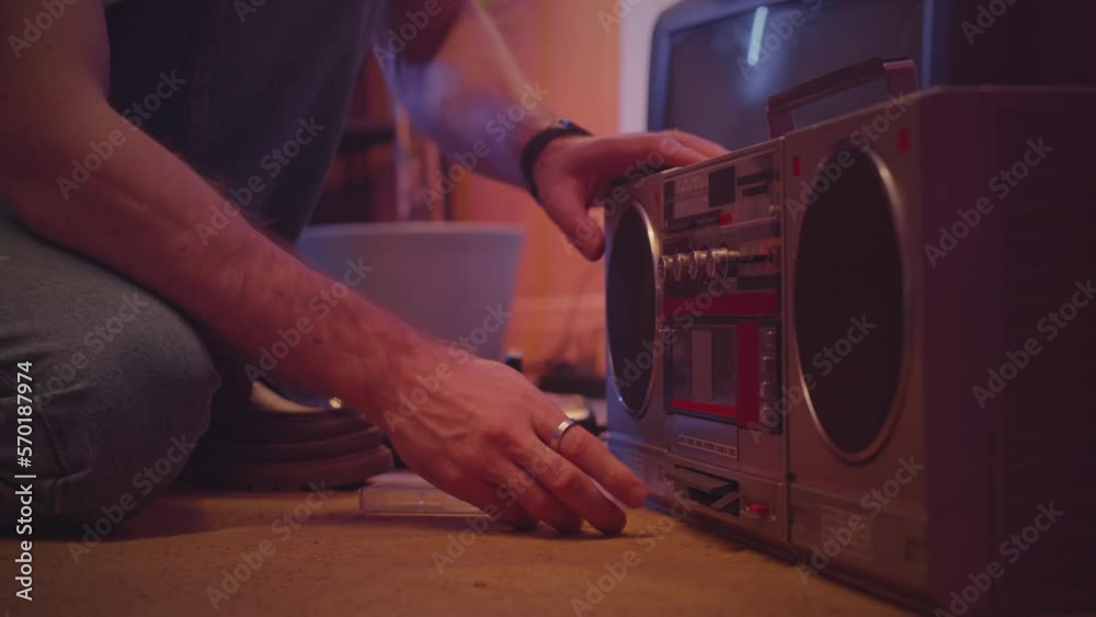 Cropped shot of unrecognizable man putting audio cassette into retro boombox stereo radio cassette recorder