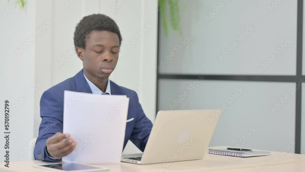 African Businessman Working on Laptop and Documents African Businessman Working on Laptop and Documents