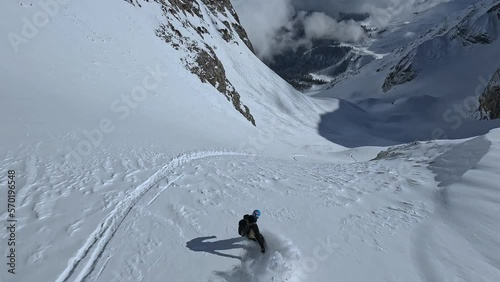 Group extreme rider flying helicopter on wild mountain snow summit ski tour north valley aerial FPV follow view. Male snowboarding riding freeride on fresh slope downhill fast dangerous heliski sport