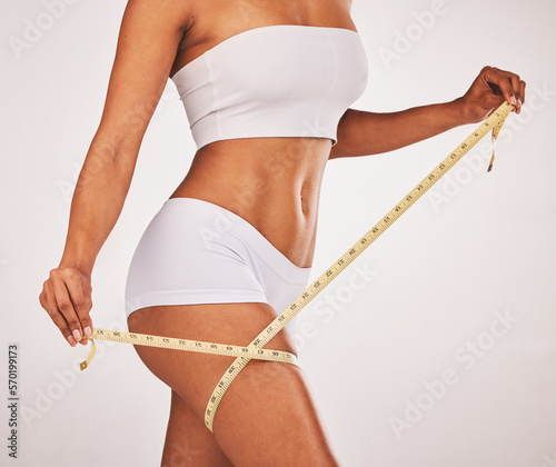 Body, woman and lose weight with tape on thigh for healthy diet, cellulite and wellness. Model on studio background for fitness, goals and motivation in underwear for exercise results and progress