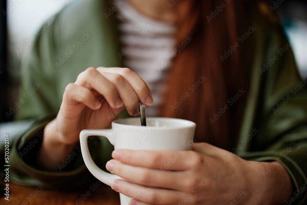 Woman in cafe stirring sugar in white coffee mug, autumn vibe and warmth Woman in cafe stirring sugar in white coffee mug, autumn vibe and warmth