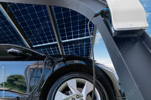 Photos Electric car is charged from a charging station that takes energy from solar panels