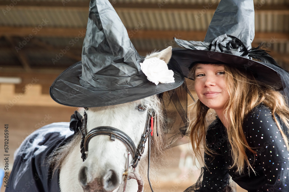 Beautiful young girl and her pony dressed up as witches for Halloween parties