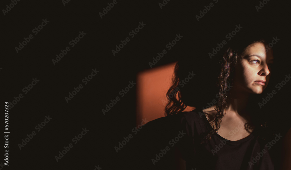 young woman on black background with light and shadow on face