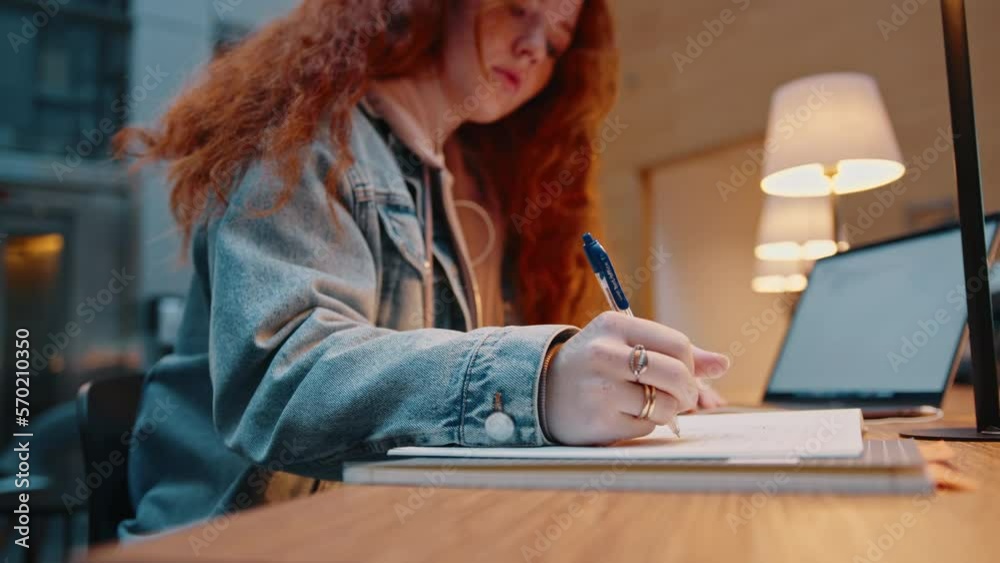 Preparing for an exam: College girl studying in a library, using a laptop to access her study material online