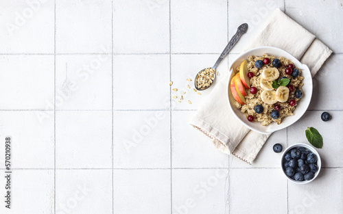 Oatmeal with fruits and berries on a white background.