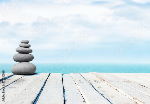 Aufeinander gestapelte Kieselsteine auf einer Holzveranda am Meer