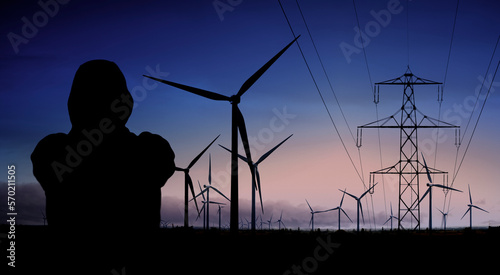 Person mit Kapuzenjacke vor windrädern und Hochspannungsleitungen