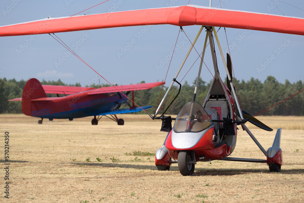 Fototapeta premium RECREATIONAL AVIATION - Powered hang glider and airplane at a field airport
