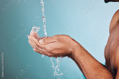 Man, water splash and hands in shower for skincare hygiene, wash or hydration against a studio background. Hand of young male model in beauty, wellness and washing or cleansing for sustainability