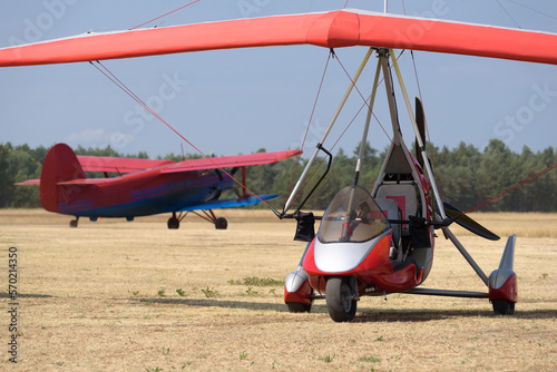  RECREATIONAL AVIATION - Powered hang glider and airplane at a field airport