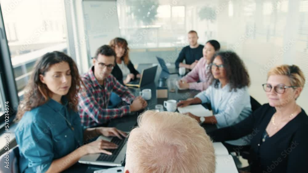 Presentation in a business meeting: Professional people sitting in a boardroom and listening to a speaker Presentation in a business meeting: Professional people sitting in a boardroom and listening to a speaker