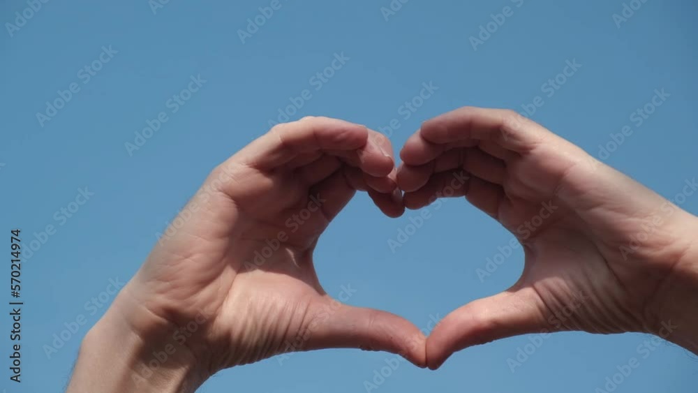 close up of men hands against a blue sky in the shape of a heart. a symbol of love, happiness and kindness. valentine's day. close up of men hands against a blue sky in the shape of a heart. a symbol of love, happiness and kindness. valentine's day.