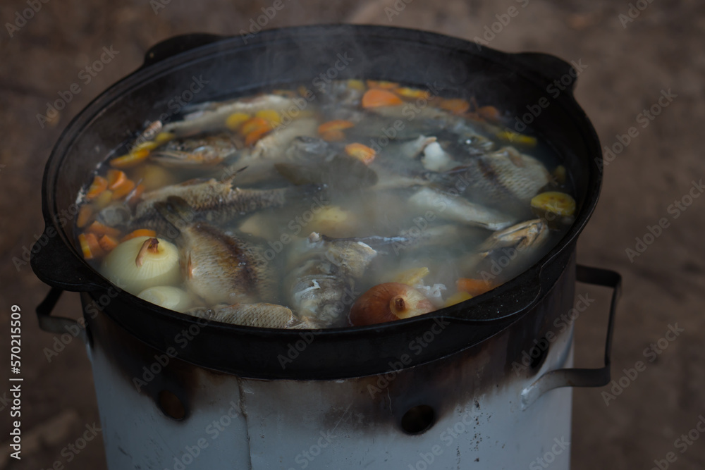 Cooking fish soup in cauldron on campfire outdoors - camp food Cooking fish soup in cauldron on campfire outdoors - camp food