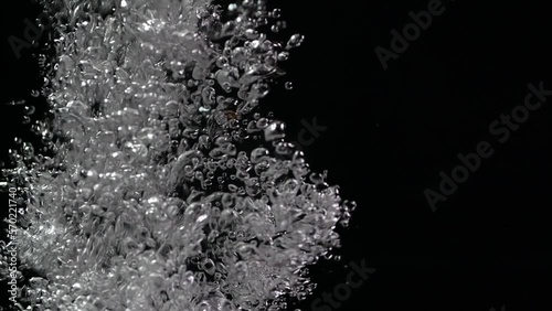 Macro shot of air bubbles rising in slow motion in water on a black background isolated. Boiling water. slow mo 200 fps photo