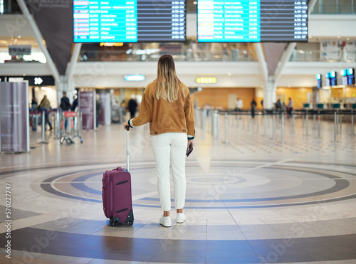Woman, airport and luggage checking flight times for travel, vacation or journey with passport in Cape Town. Female traveler standing and waiting ready for departure, boarding plane or immigration