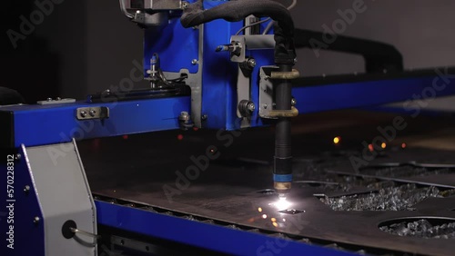 Work in the workshop for the manufacture of tin products. A cnc plasma machine cutting a hole in sheet metal. Sparks scatter beautifully in different directions. 200 fps slow motion photo