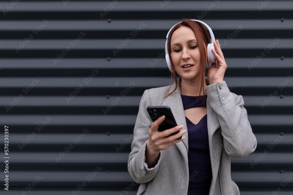red-haired businessmen on headphones near a gray wall listening to music on the phone red-haired businessmen on headphones near a gray wall listening to music on the phone