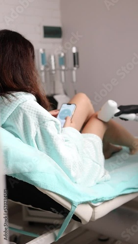 Woman relaxing on laser hair removal procedure at beauty salon with phone